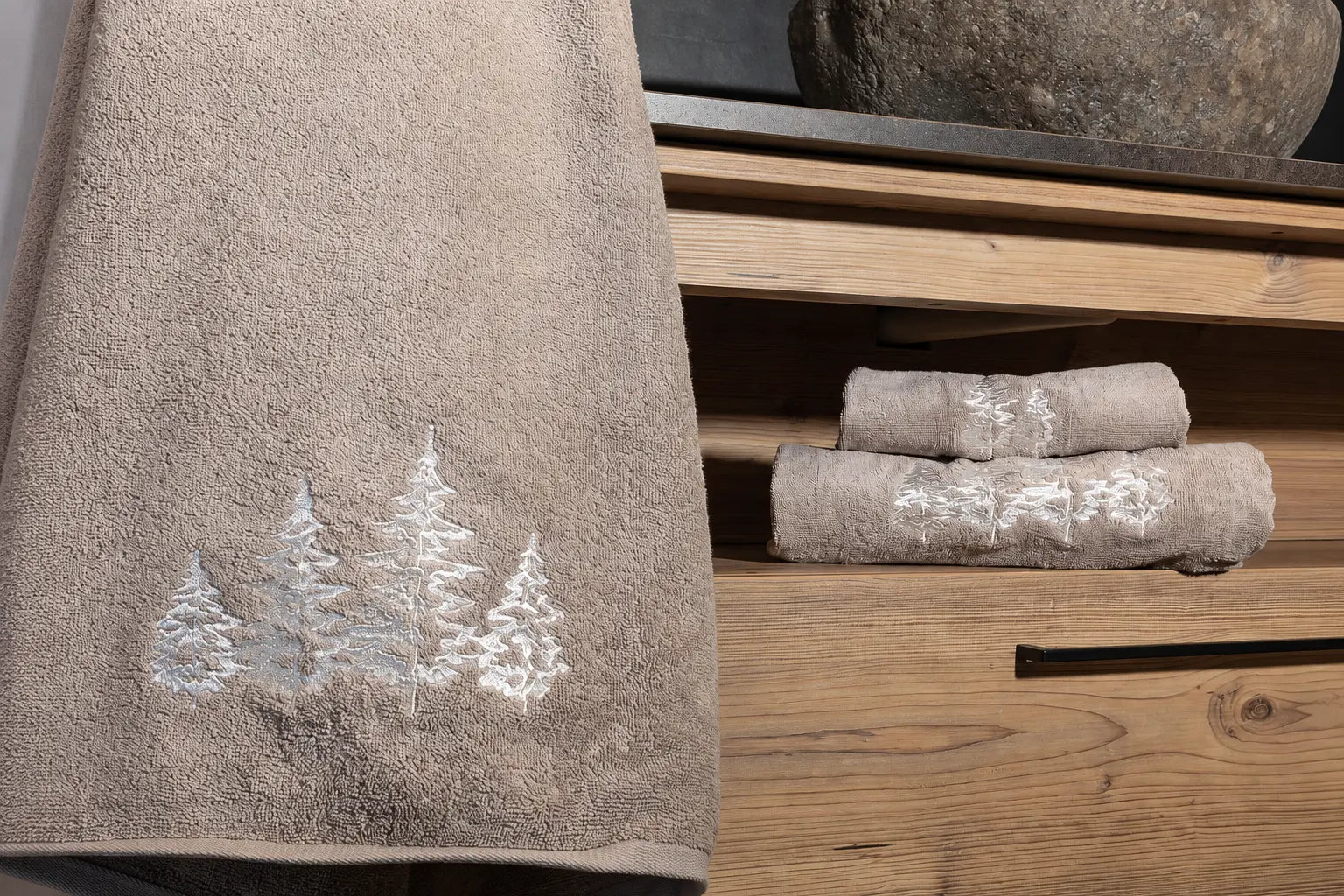 Coppia di asciugamani verdi Alberi con ricamo di abeti ambientata in un bagno in legno