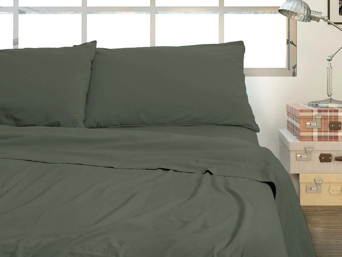 Completo lenzuola no stiro color salvia preparato su un letto
